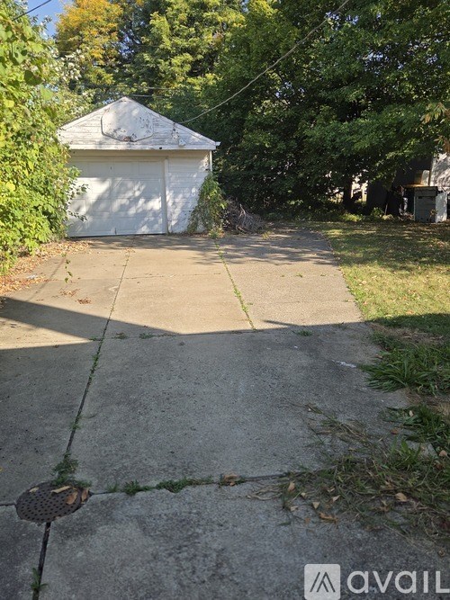 A white garage door is on the left of a concrete sidewalk.