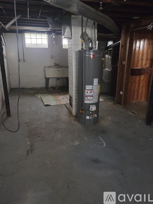 A dirty basement with a water heater and a sink.