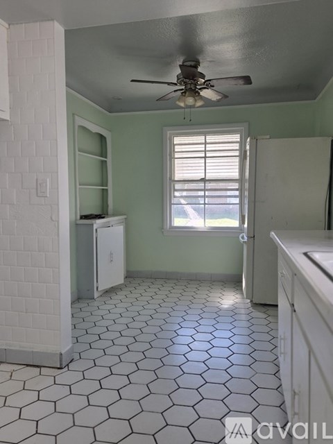 A kitchen with a white tile floor and a ceiling fan.