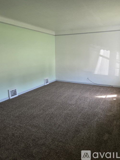 A room with a carpeted floor and a window with white curtains.