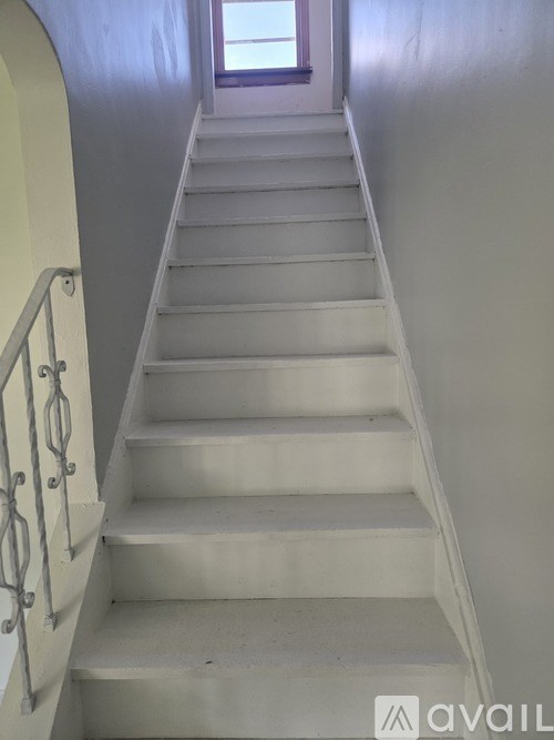 A staircase with a metal railing and a window at the top.