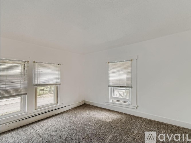 A room with two windows and carpeted floor.