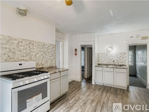 A kitchen with a white stove and a white tile backsplash.