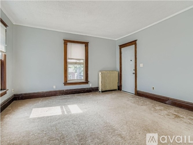 A room with a window, a door, and a radiator.