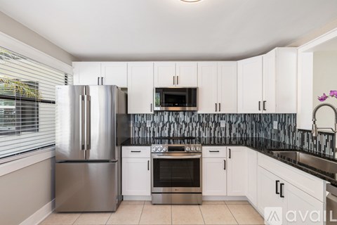 A kitchen with white cabinets and a black backsplash.