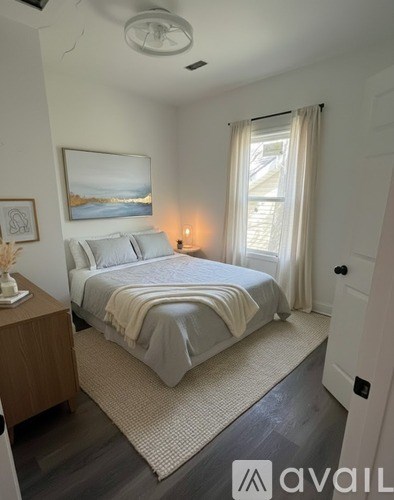 A bedroom with a bed, nightstand, and a painting on the wall.