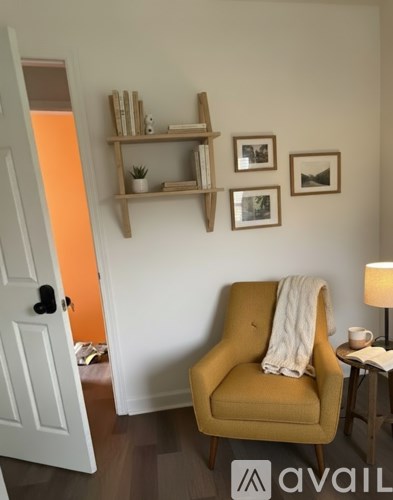 A yellow chair with a white blanket sits in a room with a white door and a small table with a lamp.