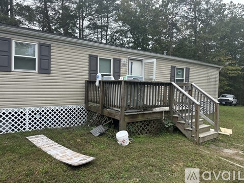 A mobile home with a deck and a white fence.