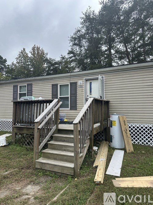 A mobile home with a deck and stairs leading to the door.
