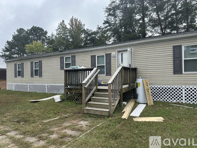 A mobile home with a deck and a white fence in the background.