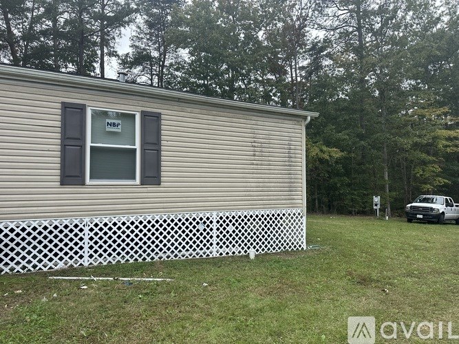 A mobile home with a white fence in front and a car parked in the background.