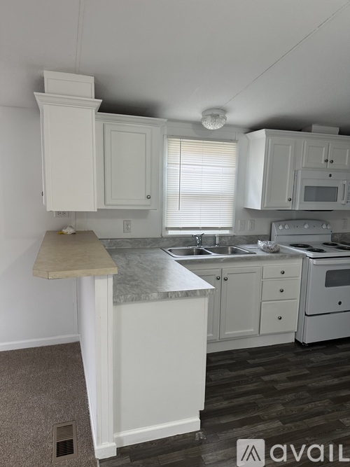 A kitchen with white cabinets and a marble countertop.