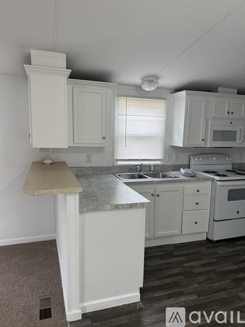 A kitchen with white cabinets and a marble countertop.