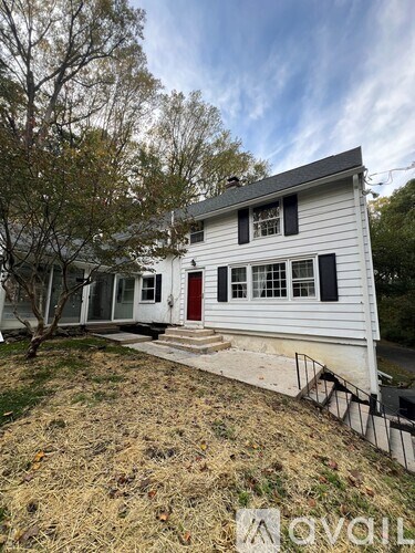 A white house with a red door and black shutters.