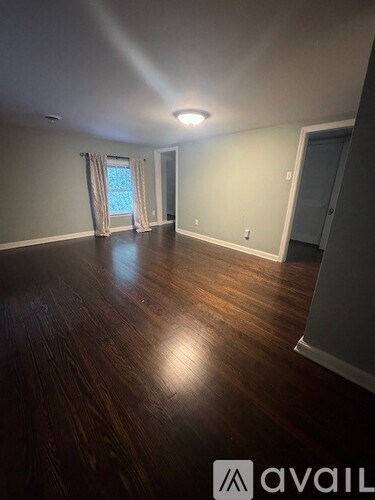 A room with wooden floors and a window with curtains.