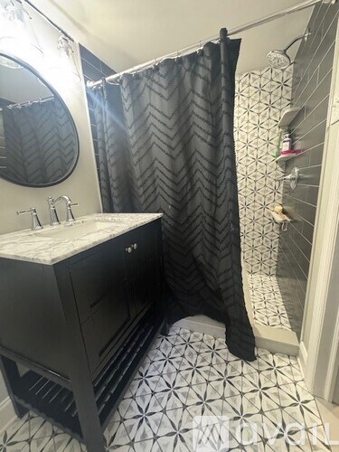 A black and white bathroom with a black shower curtain.