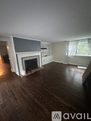 A living room with a fireplace and wooden floors.