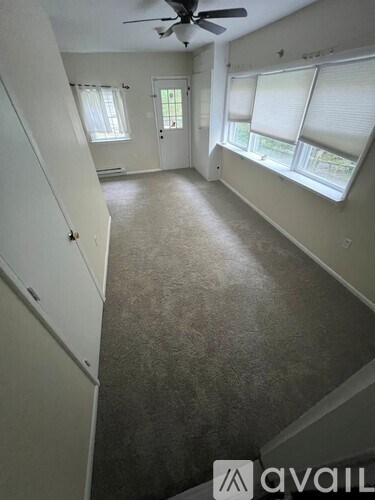 A room with a carpeted floor and a ceiling fan.