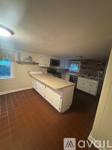 A kitchen with brown tile floors and white cabinets.