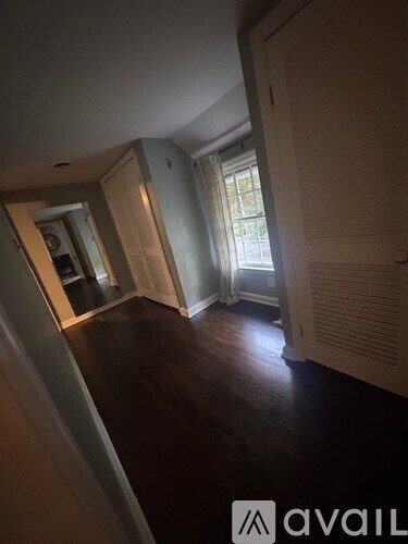 A room with wooden floors and a window with blinds.