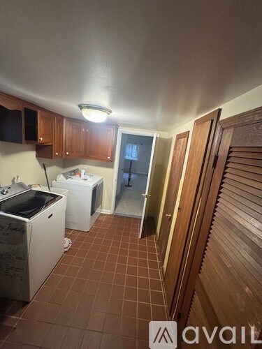 A kitchen with brown tile flooring and wooden cabinets.