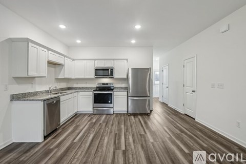 A kitchen with white cabinets and a wooden floor.