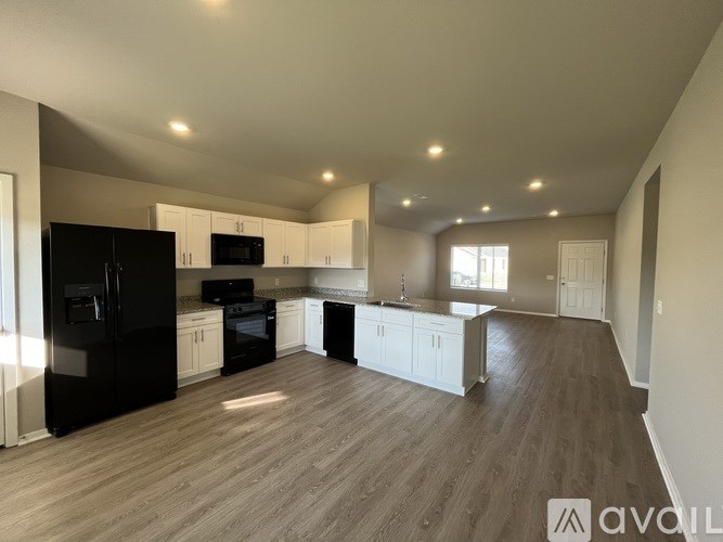 A spacious kitchen with black appliances and white cabinets.