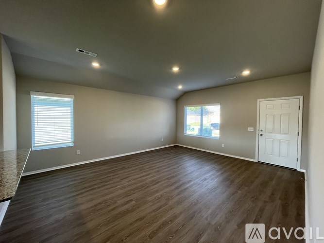 A spacious room with wooden flooring and a white door.