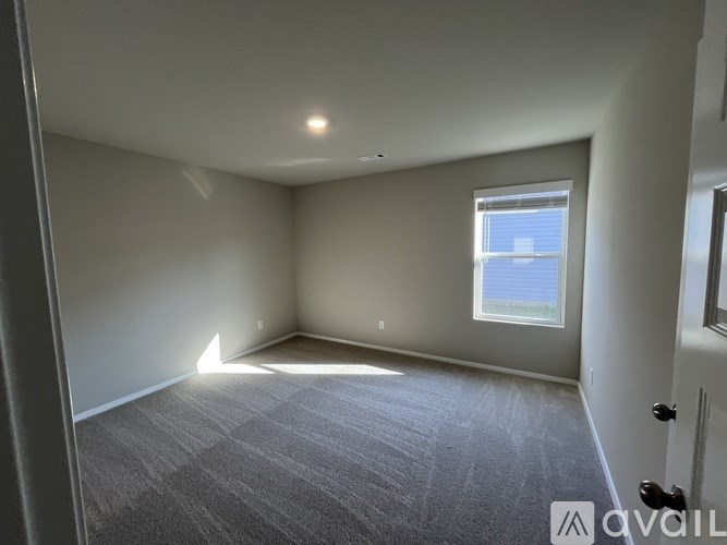 A room with a carpeted floor and a window letting in natural light.