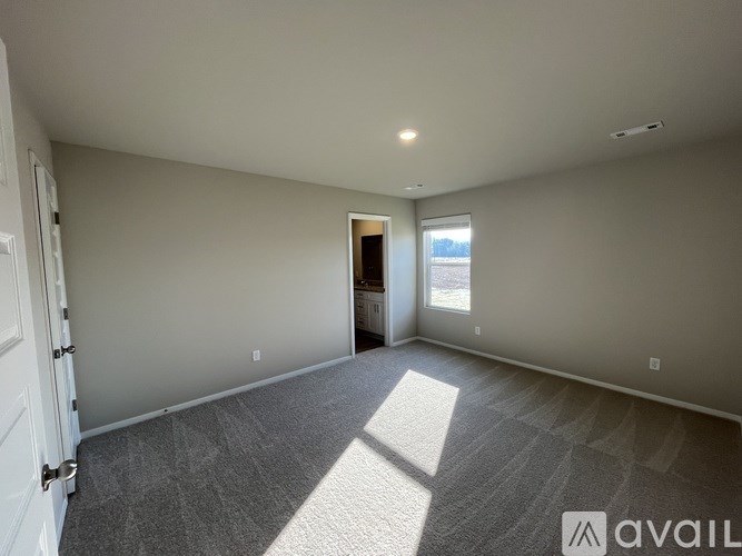 A spacious room with a carpeted floor and a door leading to another room.