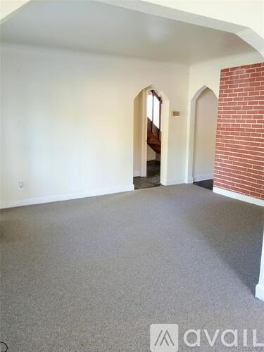 A room with a carpeted floor and a brick wall.