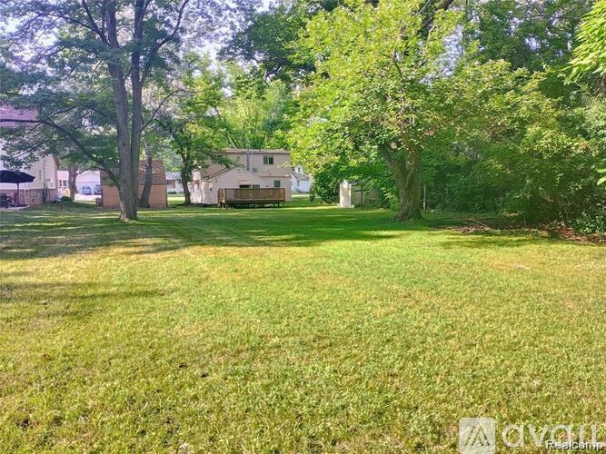 A grassy field with trees and a building in the background.