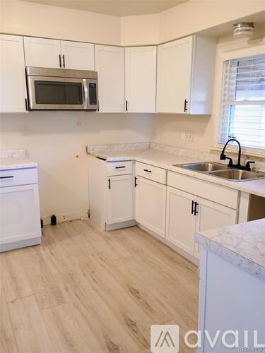 A kitchen with white cabinets and a wooden floor.