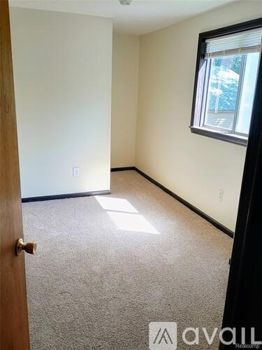 A room with a carpeted floor, a door, and a window with blinds.