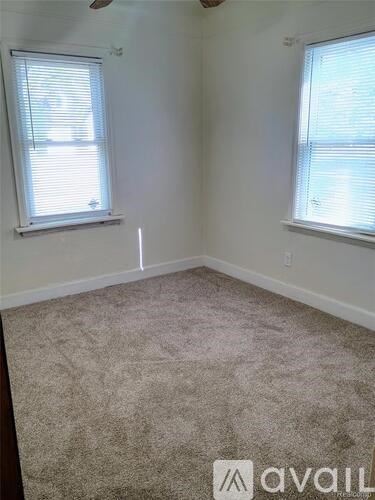 A room with two windows and carpeted floor.
