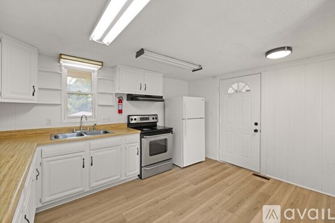 A kitchen with white cabinets and a wooden floor.