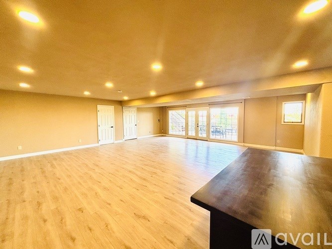 A spacious room with wooden flooring and a large window.