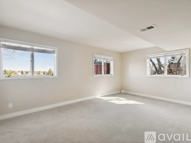 A spacious room with a large window and a smaller window on the opposite wall.