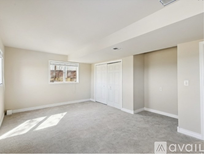 A spacious room with a carpeted floor and a window letting in natural light.