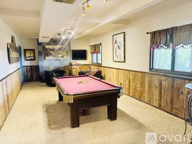 A room with a pool table and a TV.