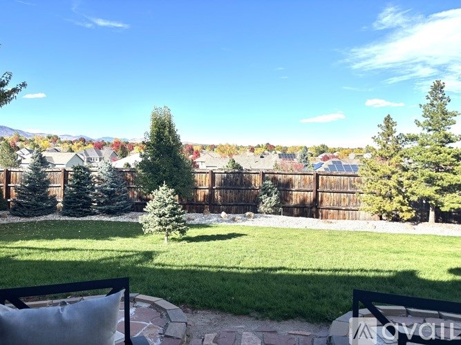 A backyard with a fence and a tree in the foreground.