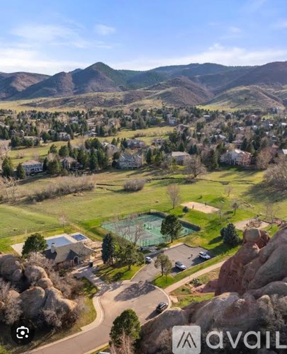 A bird's eye view of a residential area with houses, a pool, and a mountain range in the background.