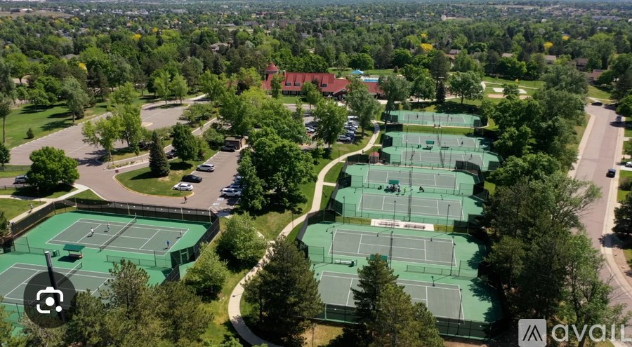 An aerial view of a tennis court surrounded by trees and buildings.