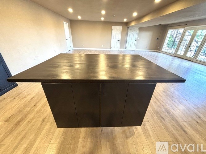 A spacious room with a large table in the center and wooden flooring.