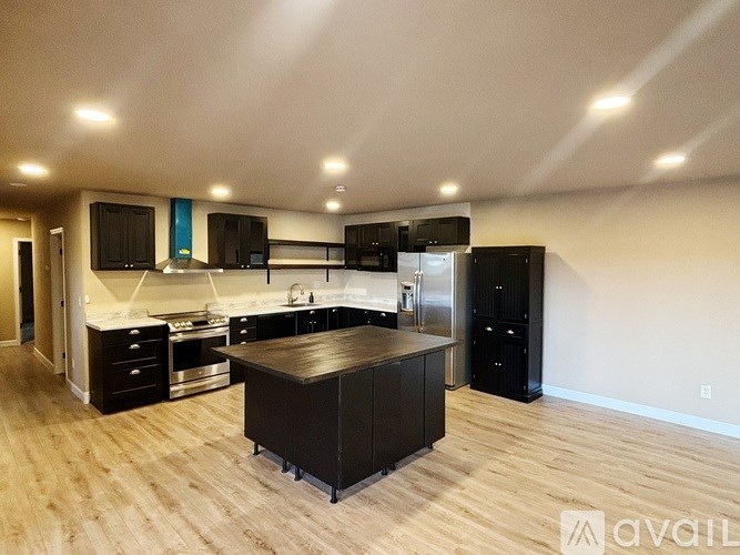 A kitchen with black cabinets and a wooden island.