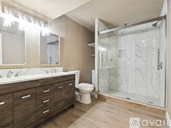 A bathroom with a marble shower and a white sink vanity.