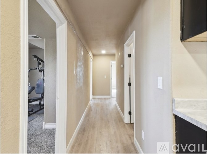 A long hallway with a door on the right and a bathroom visible in the distance.