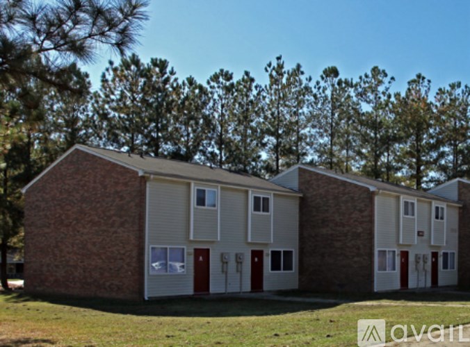 A building with a red door and white windows is surrounded by trees.