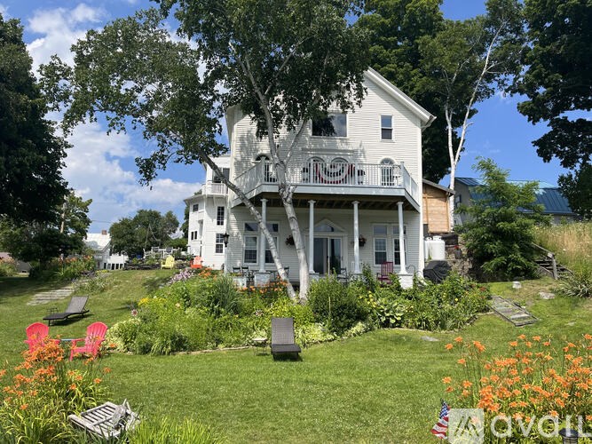 A white Victorian style house with a porch and a garden in front.