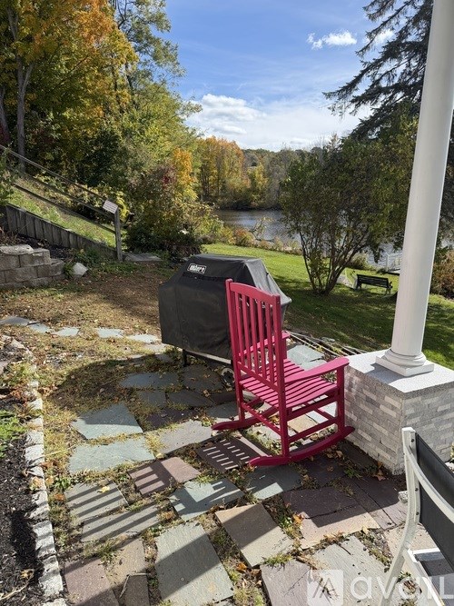 A red chair sits on a patio next to a white pillar.